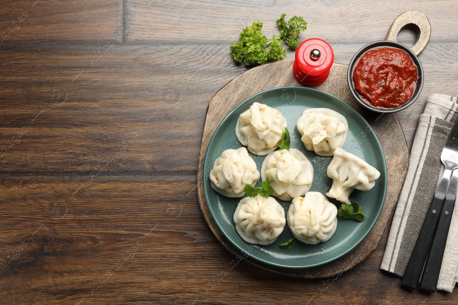 Delicious khinkali served with cilantro on wooden table, flat lay. Space for text Photo of Delicious khinkali served with cilantro on wooden table, flat lay. Space for text