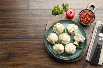 Photo of Delicious khinkali served with cilantro on wooden table, flat lay. Space for text