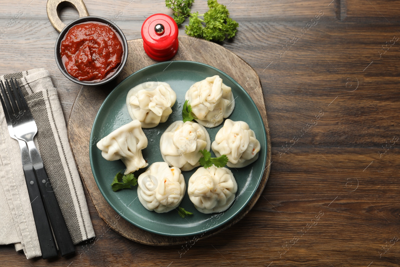 Photo of Delicious khinkali served with cilantro on wooden table, flat lay. Space for text