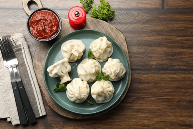 Photo of Delicious khinkali served with cilantro on wooden table, flat lay. Space for text