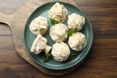 Photo of Delicious khinkali with cilantro on wooden table, top view
