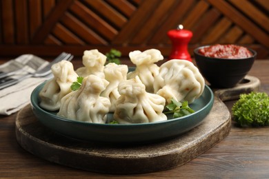 Photo of Delicious khinkali served with cilantro on wooden table, closeup
