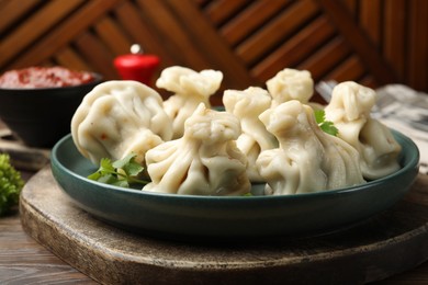 Photo of Delicious khinkali served with cilantro on wooden table, closeup