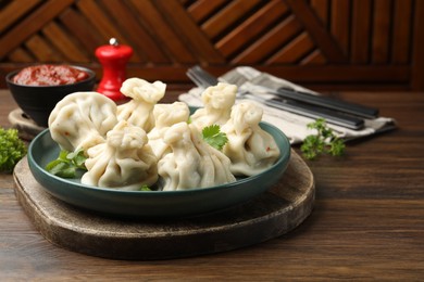 Photo of Delicious khinkali served with cilantro on wooden table, closeup