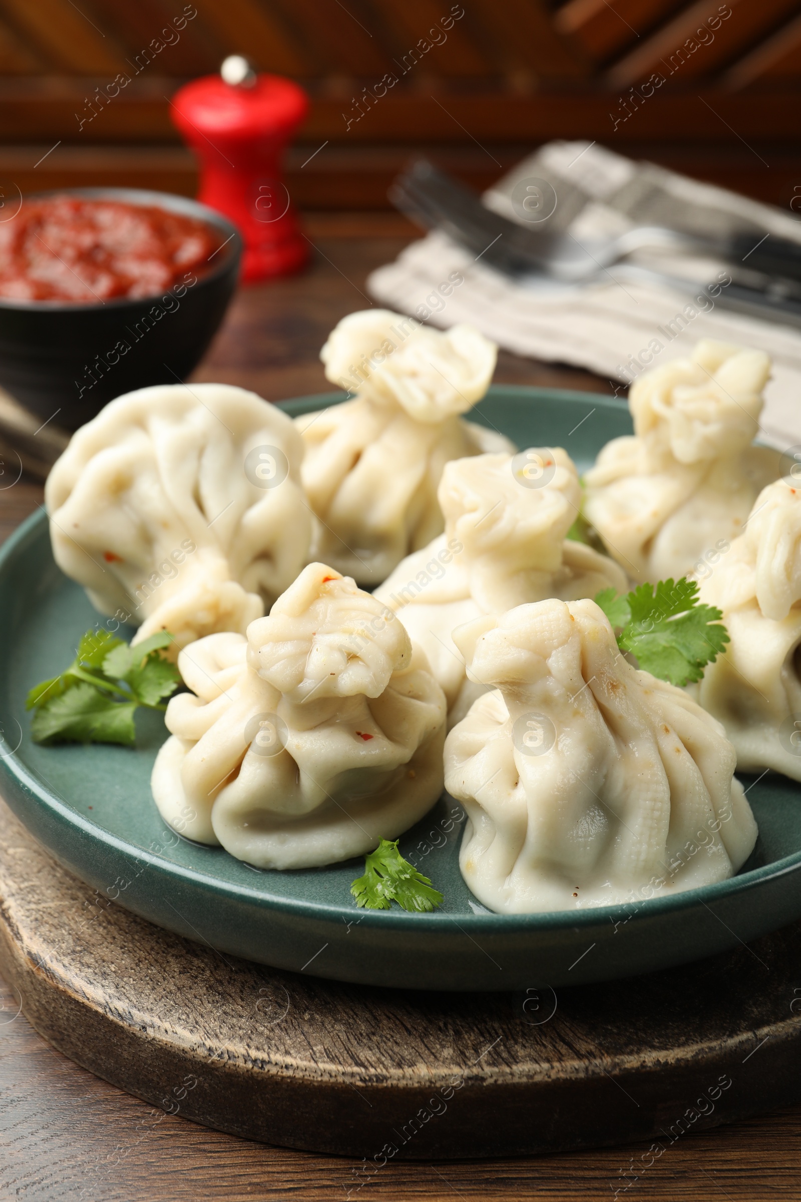 Photo of Delicious khinkali served with cilantro on wooden table, closeup