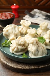 Photo of Delicious khinkali served with cilantro on wooden table, closeup