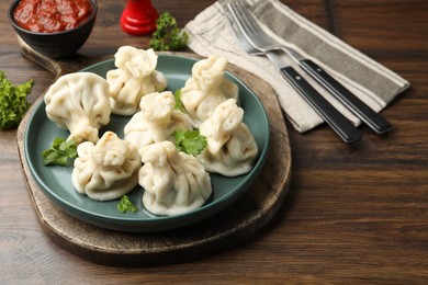 Photo of Delicious khinkali served with cilantro on wooden table, closeup