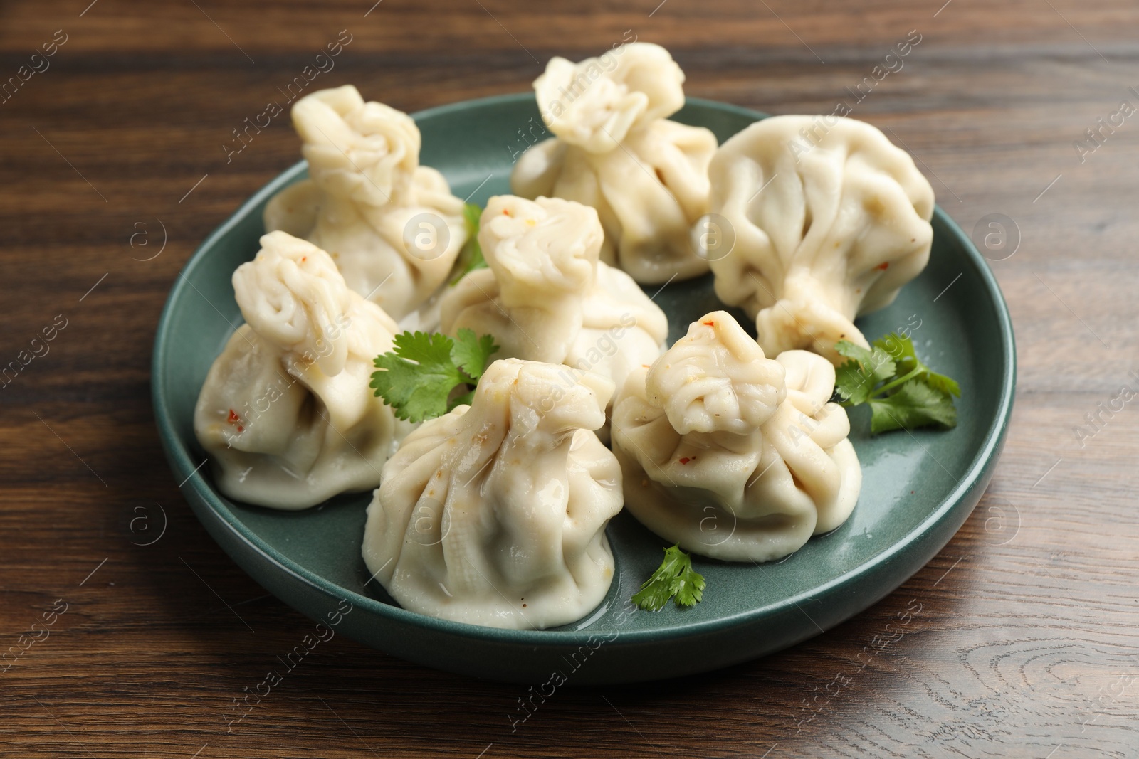 Delicious khinkali with cilantro on wooden table, closeup Photo of Delicious khinkali with cilantro on wooden table, closeup