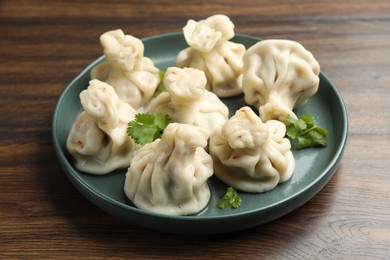 Photo of Delicious khinkali with cilantro on wooden table, closeup