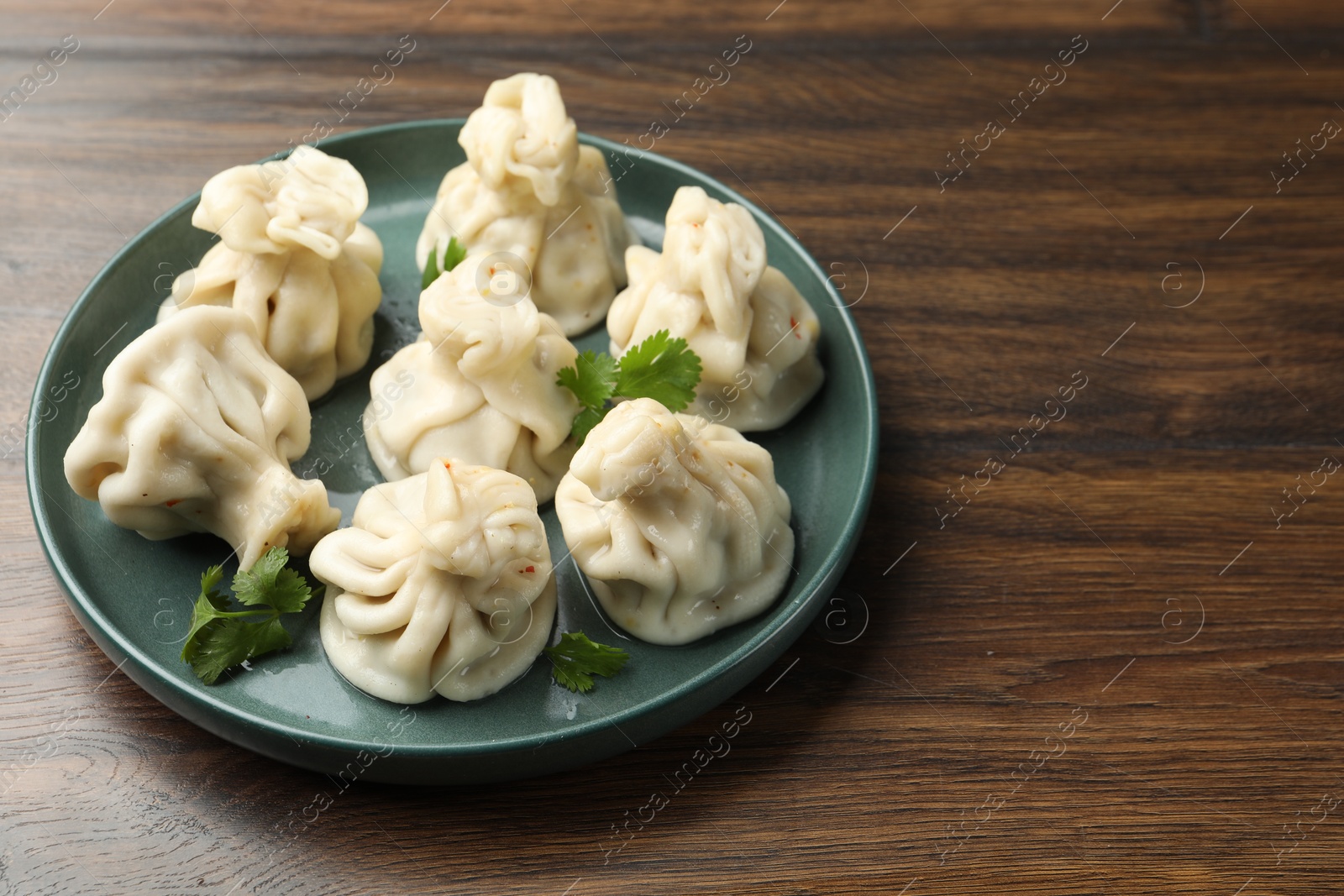 Delicious khinkali with cilantro on wooden table, closeup. Space for text Photo of Delicious khinkali with cilantro on wooden table, closeup. Space for text