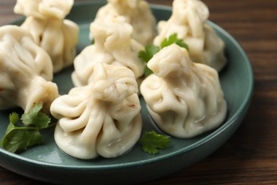 Photo of Delicious khinkali with cilantro on wooden table, closeup