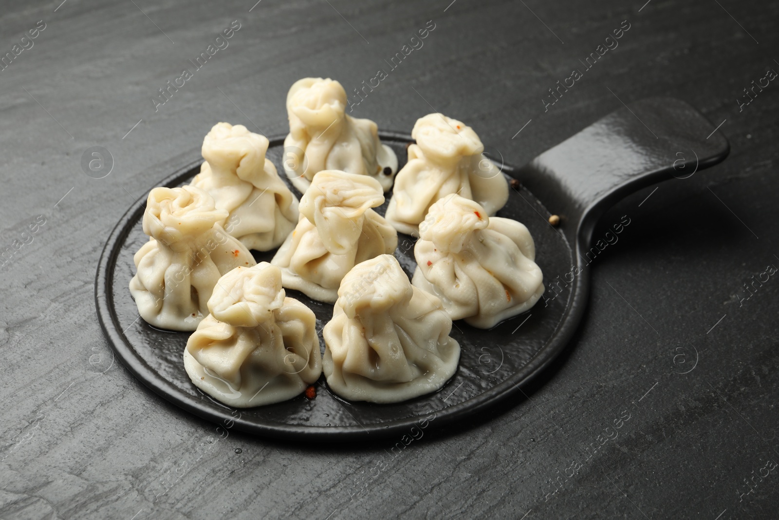 Delicious khinkali with spices on black table Photo of Delicious khinkali with spices on black table