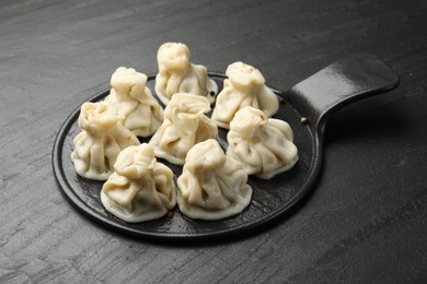 Photo of Delicious khinkali with spices on black table