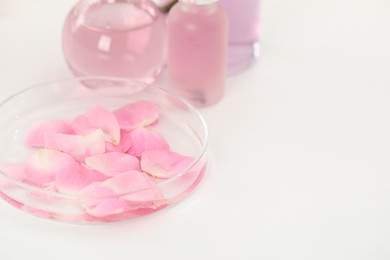 Photo of Making luxury perfume. Essential oils in glassware and flowers on white table, closeup. Space for text