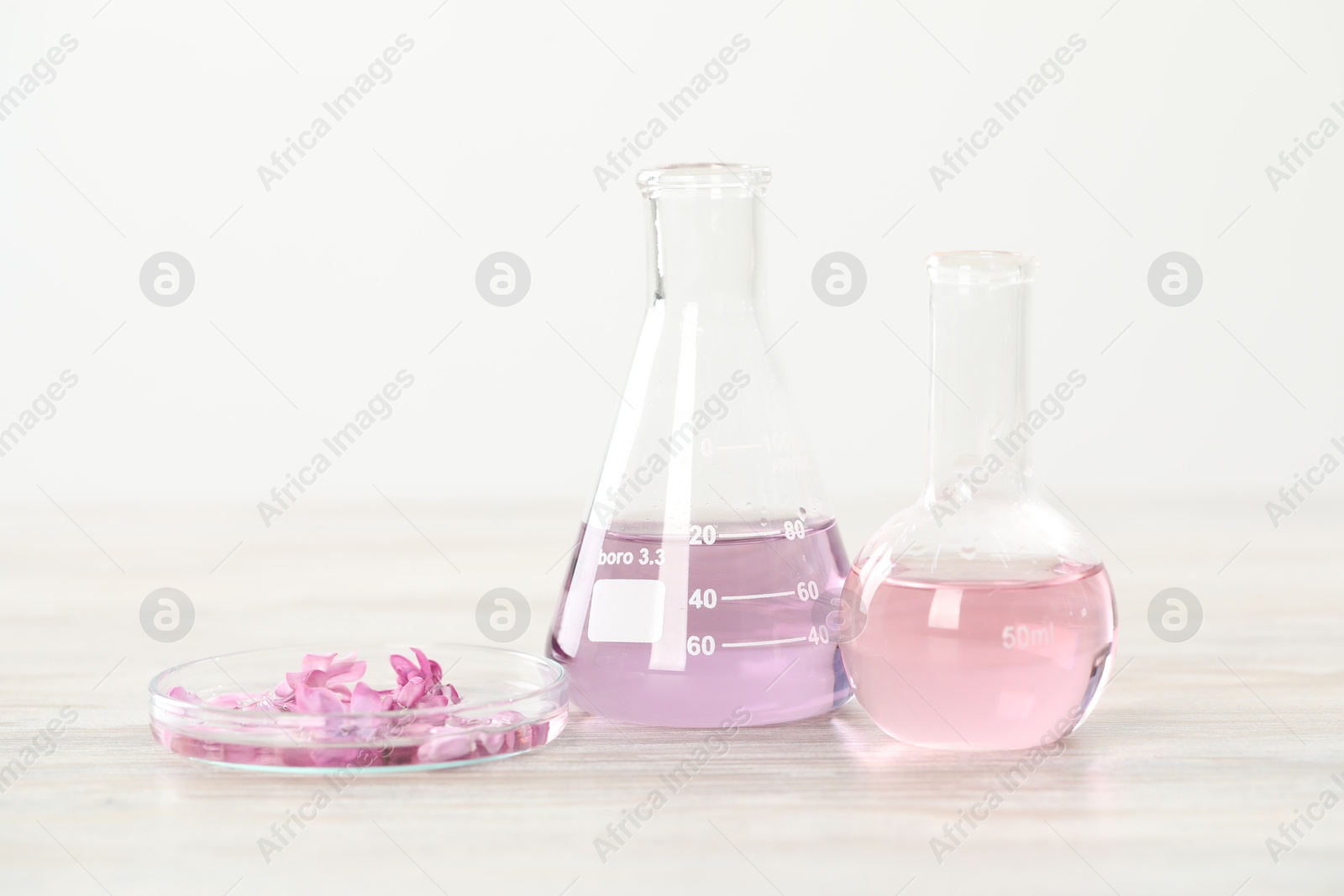 Making luxury perfume. Essential oils in glassware and flowers on white wooden table, closeup Photo of Making luxury perfume. Essential oils in glassware and flowers on white wooden table, closeup