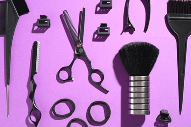 Photo of Different hairdresser's tools on violet background, flat lay