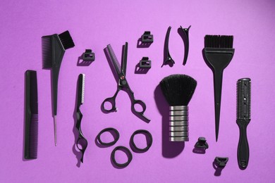 Photo of Different hairdresser's tools on violet background, flat lay