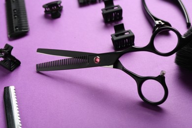Photo of Different hairdresser's tools on violet background, closeup