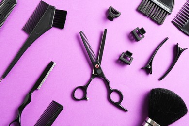 Photo of Different hairdresser's tools on violet background, flat lay