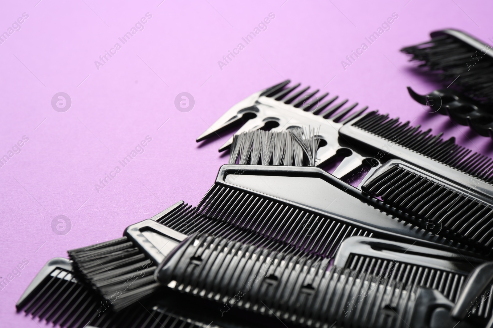 Photo of Different hairdresser's tools on violet background, closeup