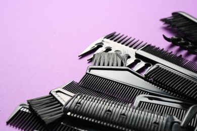 Photo of Different hairdresser's tools on violet background, closeup