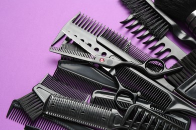Photo of Different hairdresser's tools on violet background, flat lay