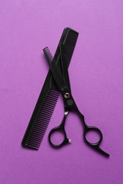 Photo of Scissors and comb on violet background, flat lay. Hairdresser's tools