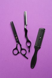 Photo of Different hairdresser's tools on violet background, flat lay