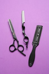 Photo of Different hairdresser's tools on violet background, flat lay