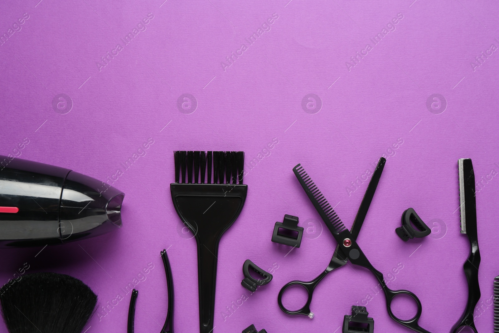 Photo of Different hairdresser's tools on violet background, flat lay. Space for text