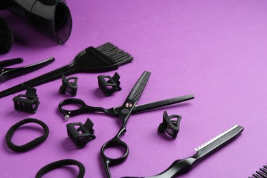 Photo of Different hairdresser's tools on violet background, closeup. Space for text