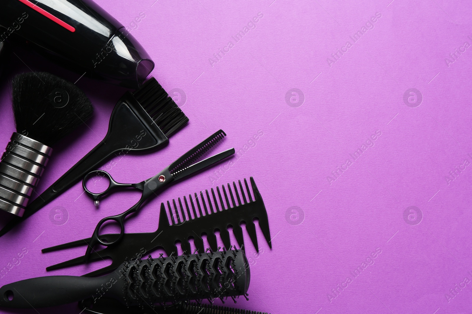 Photo of Different hairdresser's tools on violet background, flat lay. Space for text