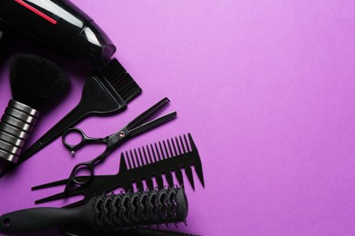 Photo of Different hairdresser's tools on violet background, flat lay. Space for text