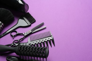 Photo of Different hairdresser's tools on violet background, space for text