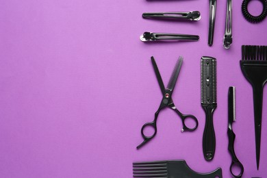 Photo of Different hairdresser's tools on violet background, flat lay. Space for text