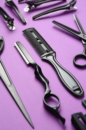 Photo of Different hairdresser's tools on violet background, closeup