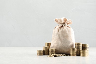 Photo of Bag and stacked coins on white table. Space for text