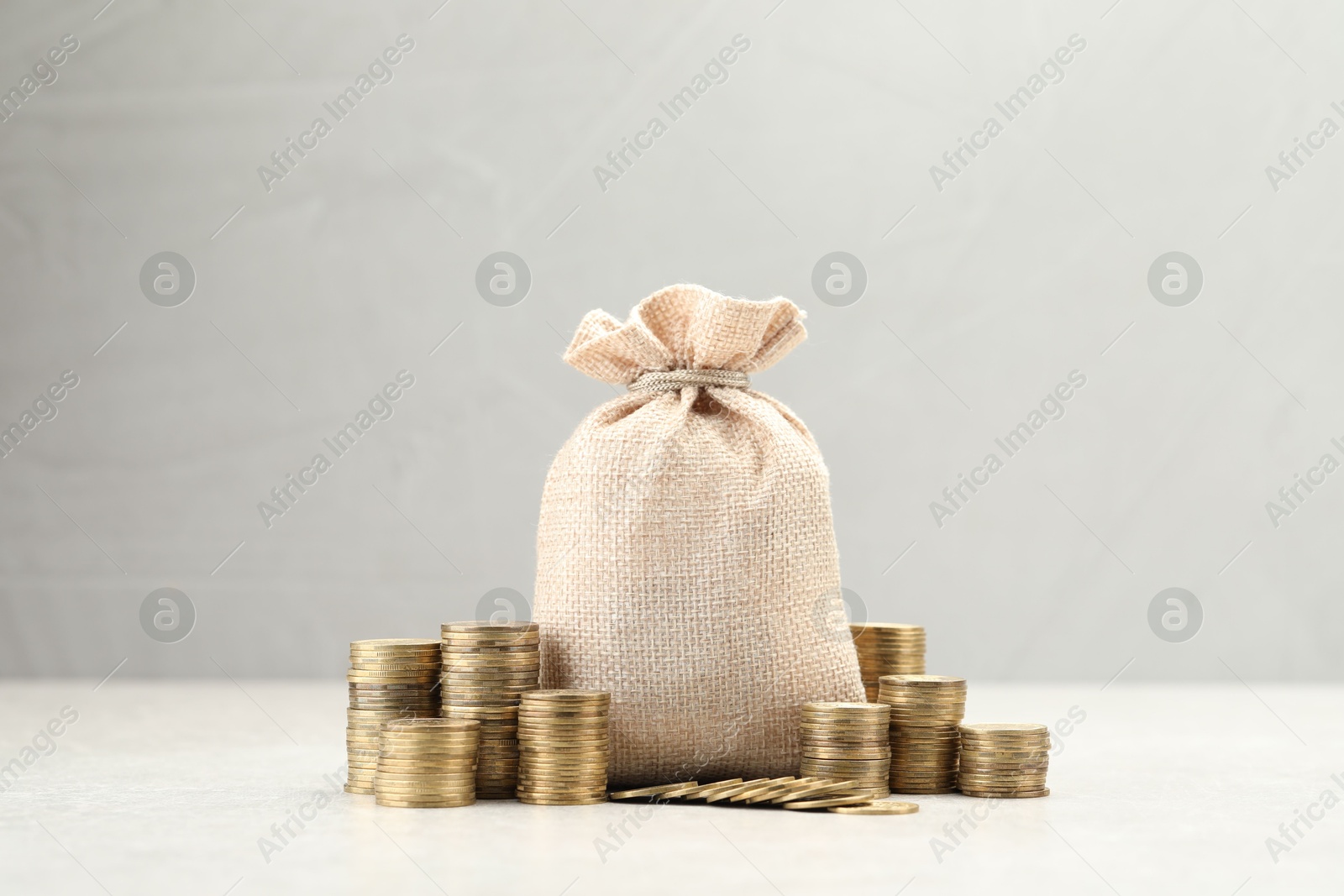 Bag and stacked coins on white table. Space for text Photo of Bag and stacked coins on white table. Space for text