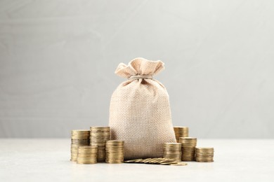Photo of Bag and stacked coins on white table. Space for text