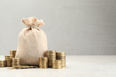 Photo of Bag and stacked coins on white table. Space for text