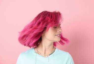Photo of Beautiful woman with bright dyed hair shaking head on pink background