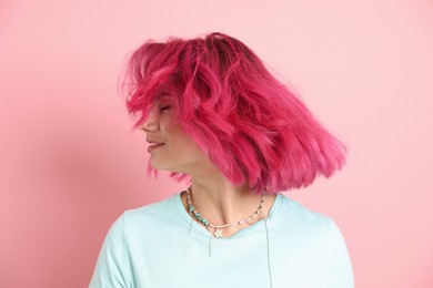 Photo of Beautiful woman with bright dyed hair shaking head on pink background