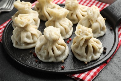 Photo of Delicious khinkali with spices on black table, closeup