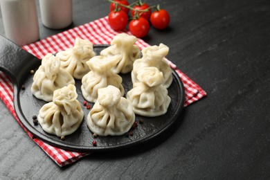Photo of Delicious khinkali served on black table, closeup. Space for text
