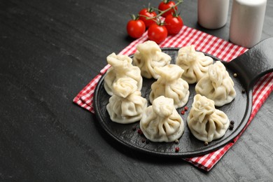 Photo of Delicious khinkali served on black table, above view. Space for text