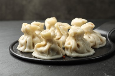 Photo of Delicious khinkali with spices on black table, closeup