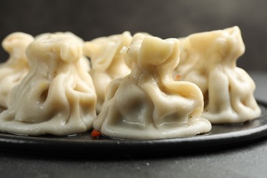Photo of Delicious khinkali with spices on black table, closeup