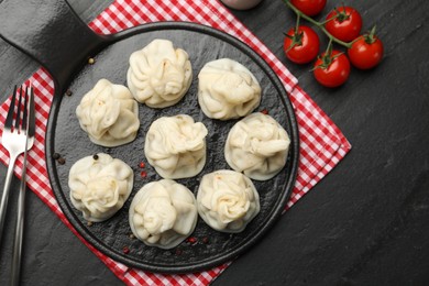 Photo of Delicious khinkali served on black table, flat lay. Space for text