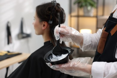 Photo of Hairdresser dyeing woman's hair in salon, closeup