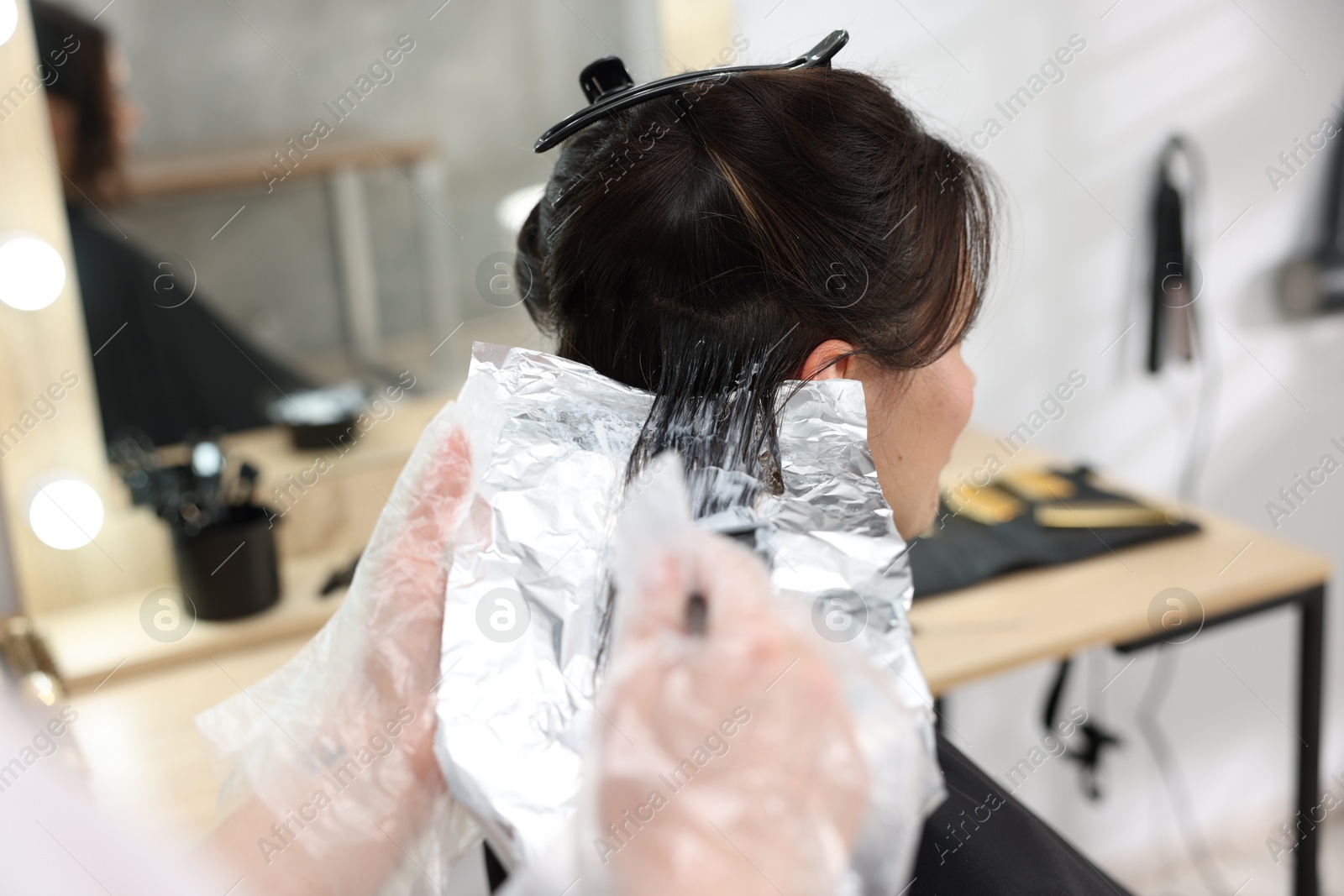 Hairdresser dyeing woman's hair in salon, closeup Photo of Hairdresser dyeing woman's hair in salon, closeup